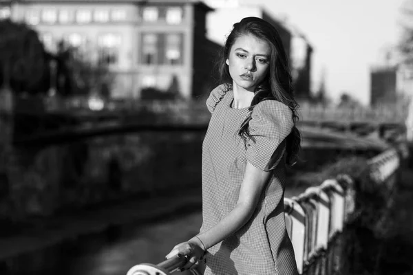 Mujer con estilo de pie junto a un río en una ciudad — Foto de Stock