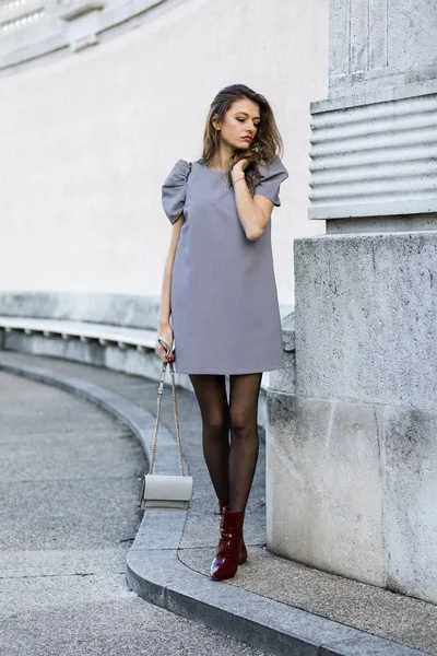 Mulher elegante vestindo vestido e botas e segurando uma bolsa — Fotografia de Stock