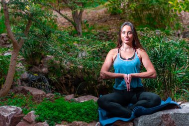 Genç bir kadın parkta yoga yapıyor ve eğitiyor. Açık hava kadınlarının sporu
