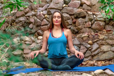 Genç bir kadın parkta yoga yapıyor ve eğitiyor. Açık hava kadınlarının sporu