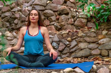 Genç bir kadın parkta yoga yapıyor ve eğitiyor. Açık hava kadınlarının sporu