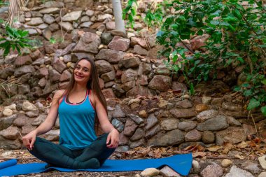 Genç bir kadın parkta yoga yapıyor ve eğitiyor. Açık hava kadınlarının sporu