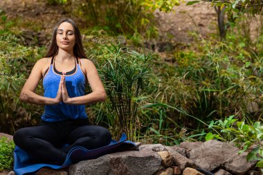 Genç bir kadın parkta yoga yapıyor ve eğitiyor. Açık hava kadınlarının sporu