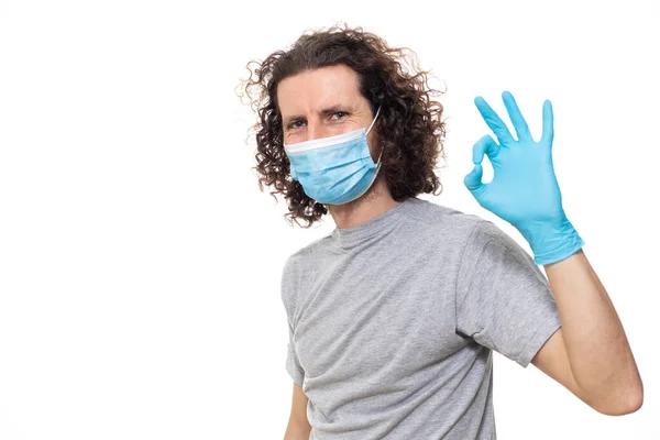 Emotional guy stands in protective medical mask with gloves against viruses and infections isolated studio. Pandemic coronavirus epidemic covid-19