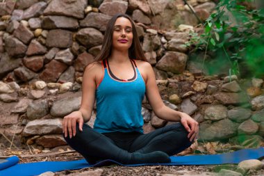 Genç bir kadın parkta yoga yapıyor ve eğitiyor. Açık hava kadınlarının sporu