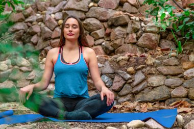 Genç kadın parkta yoga yapıyor.