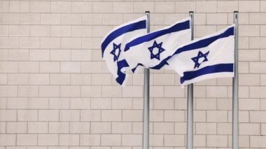 İsrail bayrağı. Üç büyük bayrak rüzgarda destansı bir şekilde tuğla duvara karşı dalgalanıyor. Ulusal sembol. Kudüs