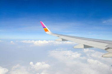 Gökyüzünde bir uçak kanadı. Uçak penceresinden beyaz bulutların üzerindeki güzel mavi gökyüzü manzarası. tatil kavramı