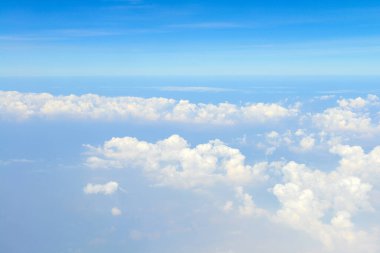 Uçak penceresinden beyaz bulutların üzerindeki güzel mavi gökyüzü manzarası 