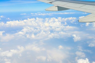 Gökyüzünde bir uçak kanadı. Uçak penceresinden beyaz bulutların üzerindeki güzel mavi gökyüzü manzarası. tatil kavramı