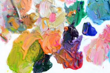 Bir palette farklı renkte renkli yağlı boya ve beyaz arkaplanda fırçalar