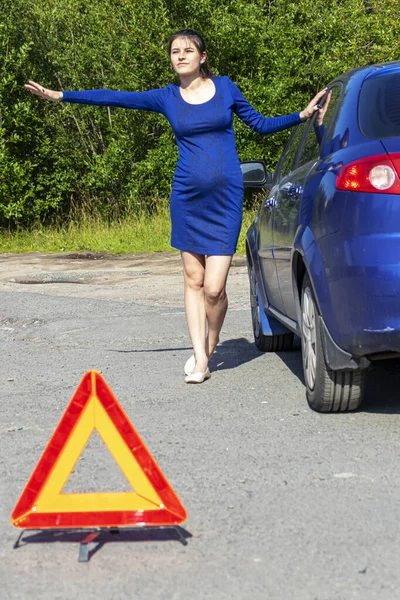 Foto di giovane donna con mano alzata in piedi vicino a un'auto rotta con cappuccio aperto. Concetto assicurazione auto — Foto Stock