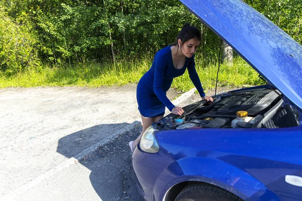 Giovane donna vicino rotto auto ha bisogno di assistenza guardando sotto cappuccio aperto. Concetto assicurazione auto — Foto Stock