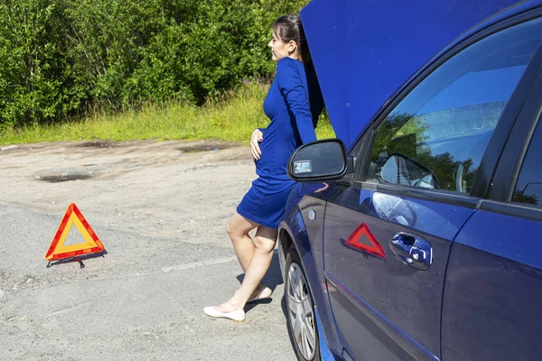 Женщина с аварийным знаком "Стоп" голосует на дороге. Концепция страхования автомобиля — стоковое фото