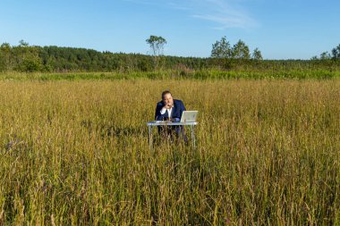 Sakallı, beyaz, beyaz, beyaz bir adam dışarıda bir laptopta çalışıyor. Kavramsal iş adamı açık havada.