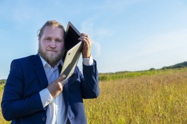 Sakallı beyaz bir beyaz adam dışarıda bir laptopta konuşuyor. Kavramsal iş adamı açık havada.