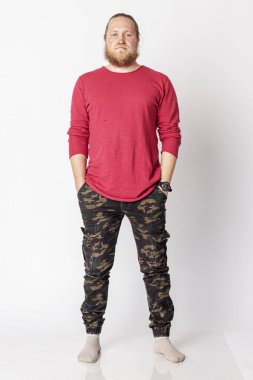 Beyaz arka planda kırmızı kazaklı, sakallı beyaz bir adam.