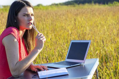 Doğada dizüstü bilgisayarı olan beyaz bir kız.