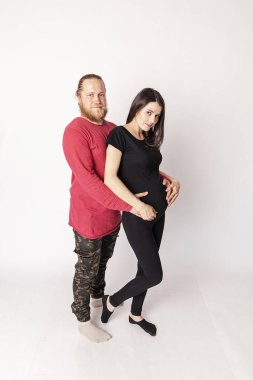 Kırmızı kazaklı beyaz adam hamile bir Cauc 'a sarılıyor.