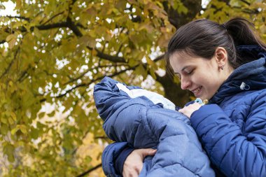 Genç beyaz anne kucağında yeni doğmuş bir bebeği tutuyor.