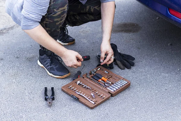 White man takes tools from a suitcase for car repair — Stock Photo, Image