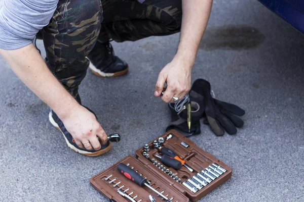 Weißer Mann entwendet Werkzeug aus Koffer für Autoreparatur — Stockfoto