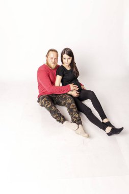 Kırmızı kazaklı beyaz adam hamile bir Cauc 'a sarılıyor.