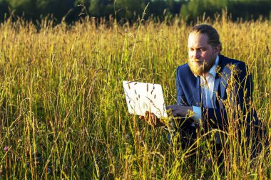 Doğada dizüstü bilgisayarı olan beyaz bir adam. Kavramsal işadamı 