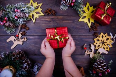 Sezon dekorasyon ile çerçeveli Noel ve yeni yıl ahşap arka plan. Kış tatil Tema. Bir hediye bebek el ele tutuşur