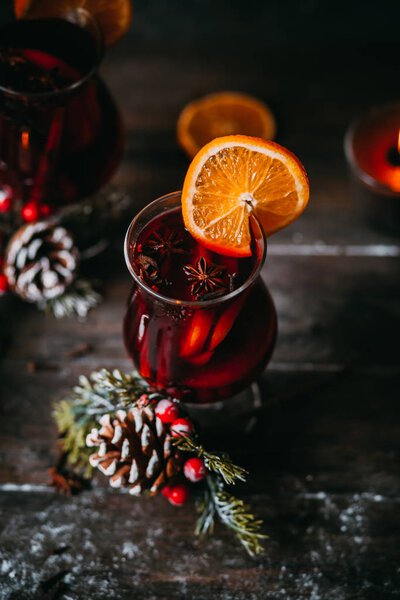 christmas hot mulled wine with spices, candle and traditional New Year decorations and orange on wooden background