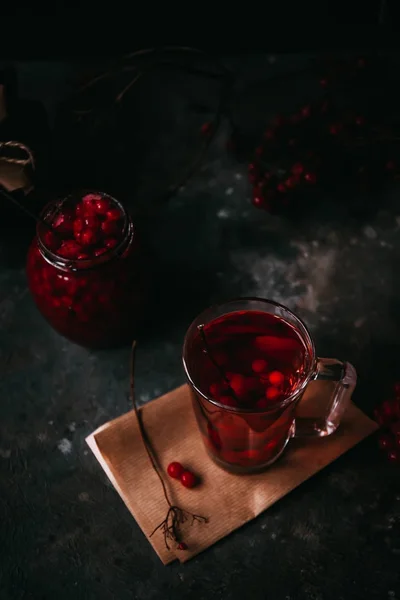 Thé chaud à base de canneberge. Confiture maison dans un bocal en verre sur un fond sombre. Boisson de Noël d'hiver — Photo