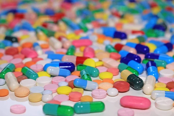 Colorful capsules with pills and tablets on white table, medical treatment