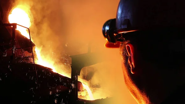 鋳造所内の液体金属 炉内の溶解鉄 製鉄所 炉内の鉄製錬を管理するゴーグル及びヘルメットを有する労働者は ベース金属を抽出するために鉱石に熱を加える — ストック写真