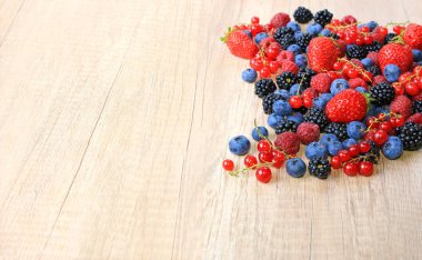 Ahşap arka planda taze böğürtlen, çilek, yabanmersini, ahududu, böğürtlen ve kuşüzümü karışımı.