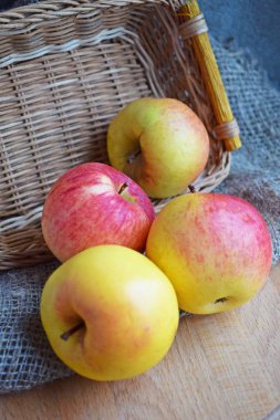 Tahta bir arka planda hasır sepette güzel olgun elmalar..