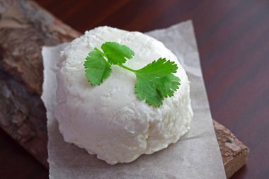 Homemade pickle cheese with a sprig of greenery on a wooden background.