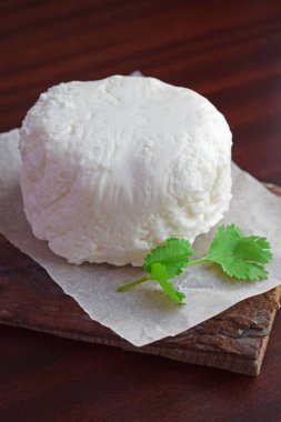Homemade pickle cheese with a sprig of greenery on a wooden background.