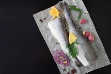 Siyah arka planda otlu, baharatlı ve limonlu taze deniz balığı..