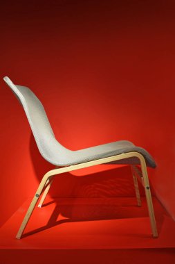 Comfortable grey chair on a red background.