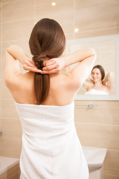 Улыбающаяся женщина, заплетающая волосы
