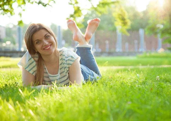 gülümseyen genç kadın çim üzerinde yalan
