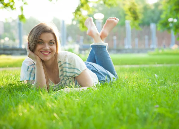 Lachende jonge vrouw liggen op gras — Stockfoto