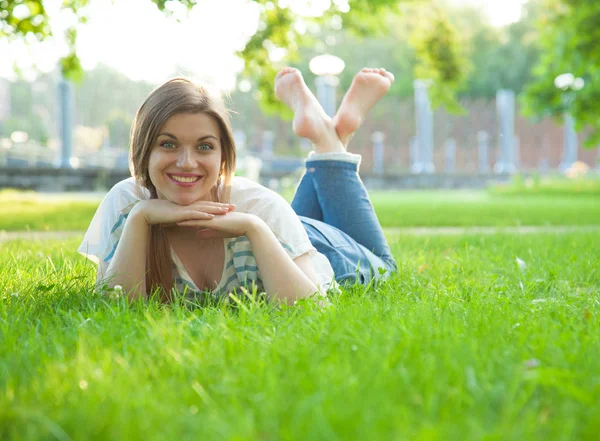 Lachende jonge vrouw liggen op gras — Stockfoto