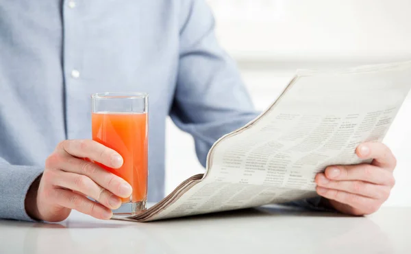 Hombre leyendo periódico con jugo — Foto de Stock