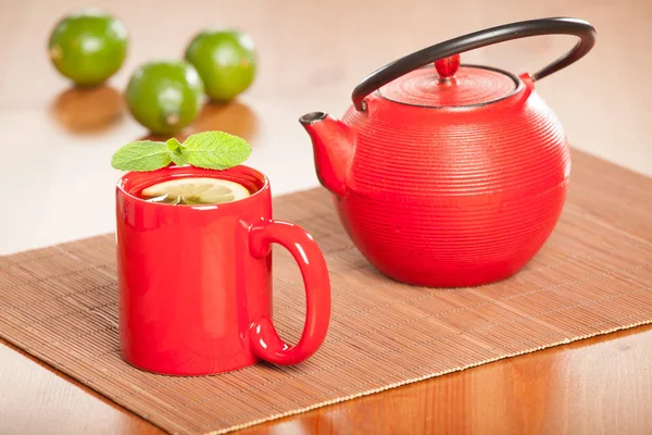 Teekanne und Tasse Tee mit Limette und Minze — Stockfoto