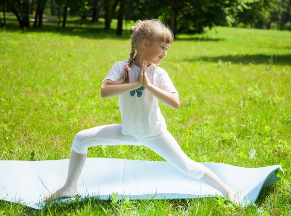 Mała dziewczyna robi ćwiczenia w parku — Zdjęcie stockowe