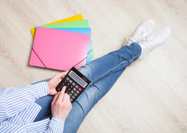 Femme utilisant une calculatrice assise sur le sol — Photo