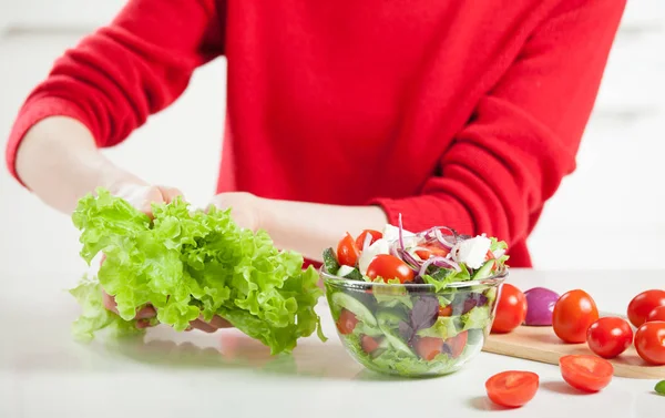 野菜サラダを料理赤いセーターの女性 — ストック写真