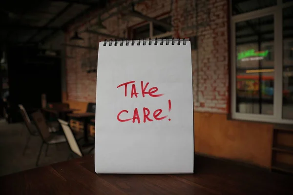 Take care text written on a paper on the empty cafe table — Stock Photo, Image