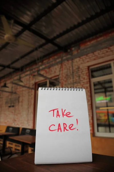 Take care text written on a paper on the street cafe table — Stock Photo, Image